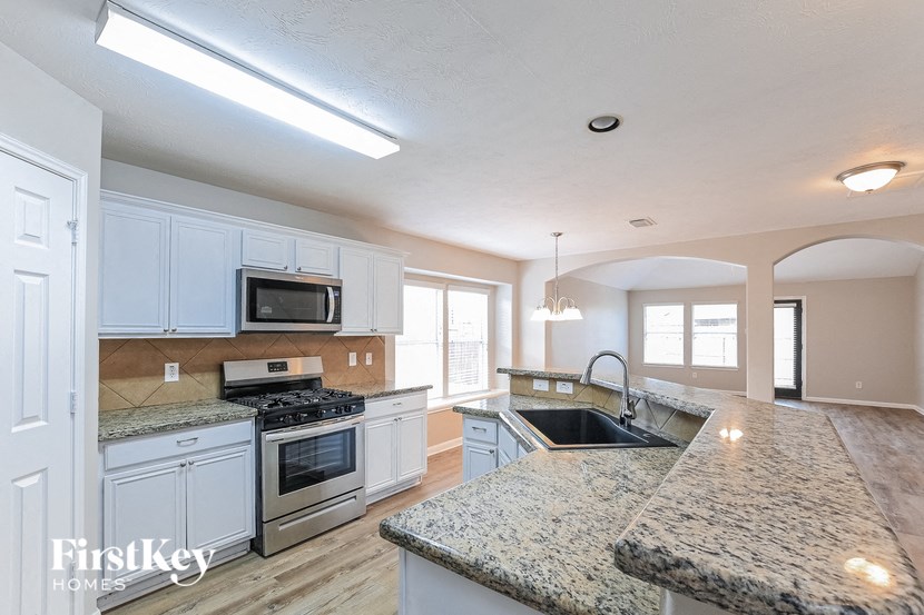a large kitchen with white cabinets and granite counter tops