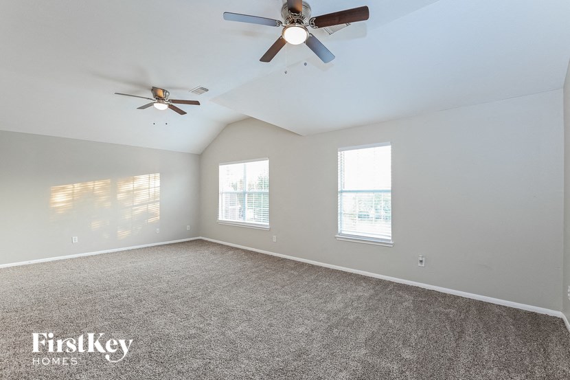 an empty living room with a ceiling fan and two windows