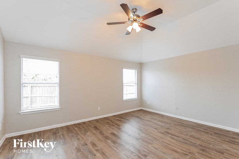 an empty living room with a ceiling fan and wood floors