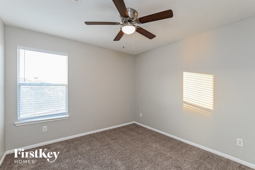 an empty bedroom with a ceiling fan and two windows