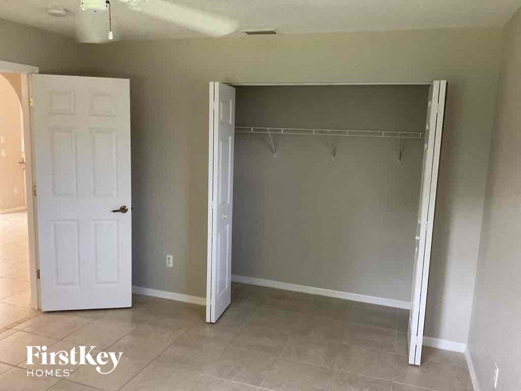 A bedroom with a white door and a white closet with a shelf.