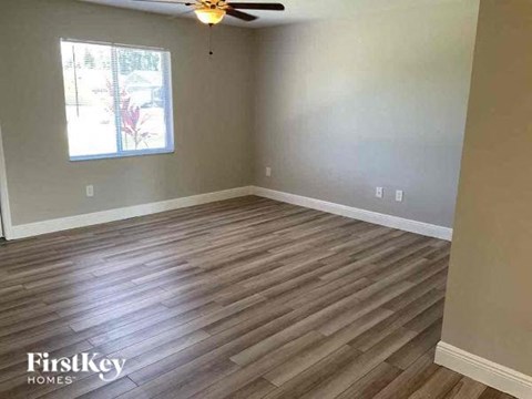 a empty living room with wood floors and a ceiling fan
