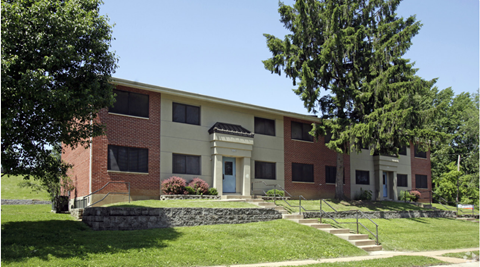 the front of a building with a green lawn and trees