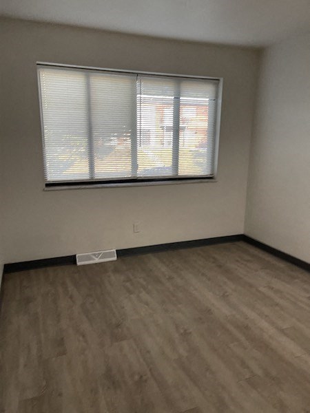 an empty room with a window and wooden floors