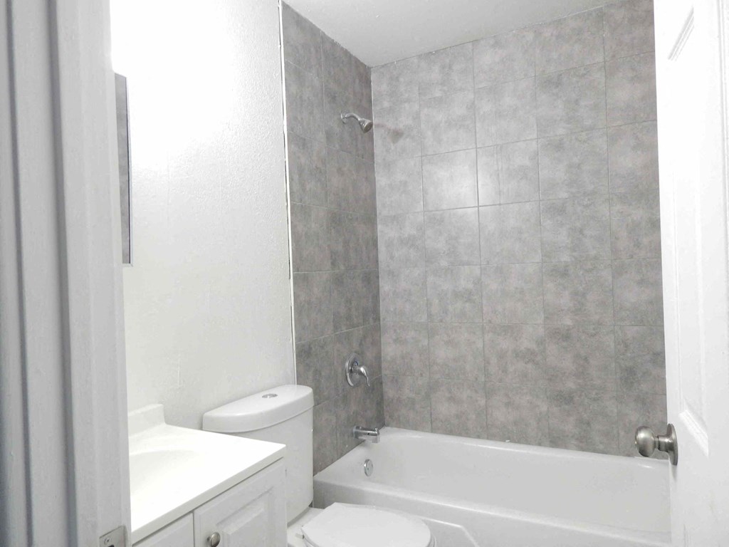 a white bathroom with a tub and a toilet and a sink