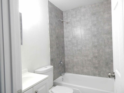 a white bathroom with a tub and a toilet and a sink