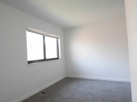 an empty room with a window and white walls
