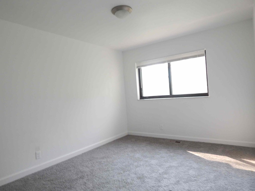 an empty room with a window and carpet