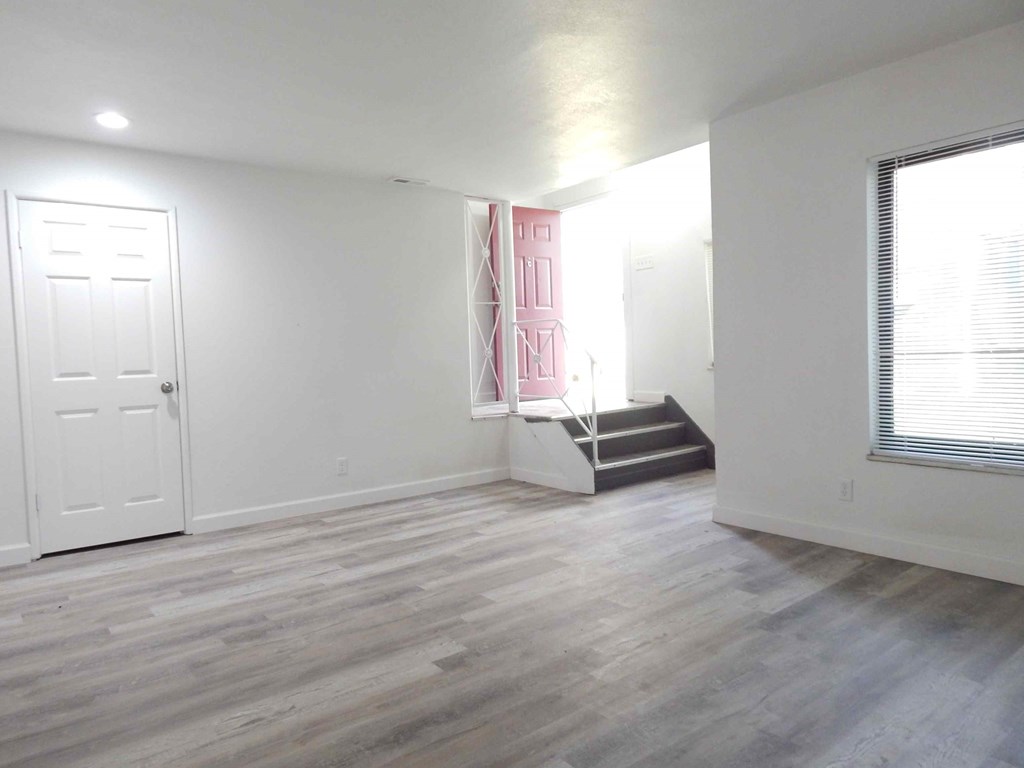 an empty living room with white walls and wood floors