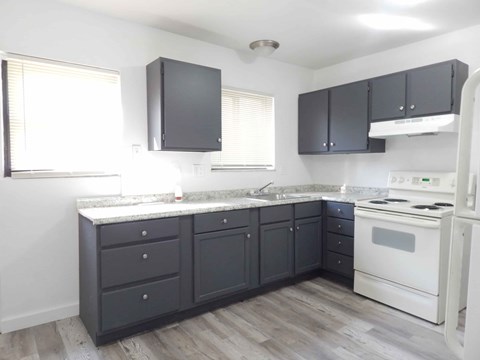 A kitchen with a white stove and black cabinets.
