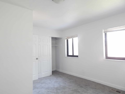 A room with a white door, window, and carpeted floor.