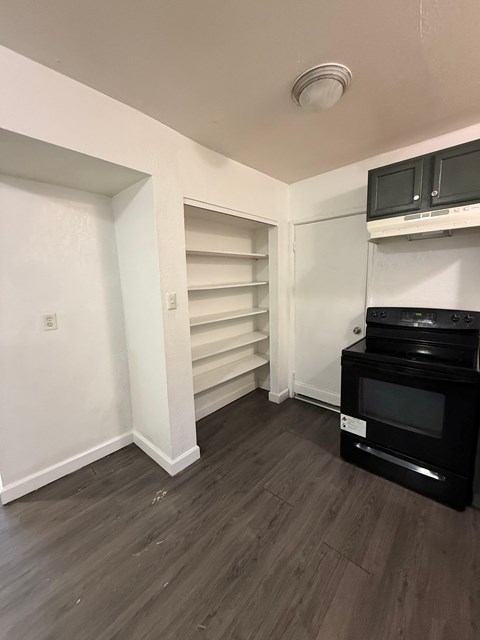A kitchen with a black oven and microwave, and white cabinets.