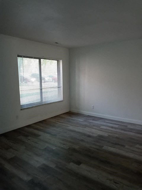 an empty living room with a window and wooden floors