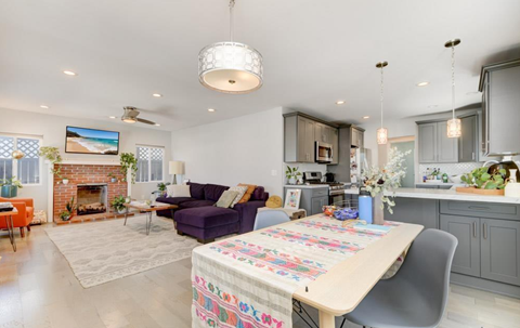 A well-lit, modern kitchen and living room with a dining table set for two.