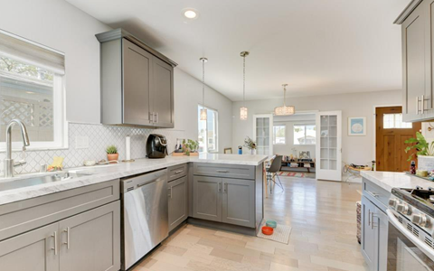 A kitchen with a white counter top and grey cabinets.
