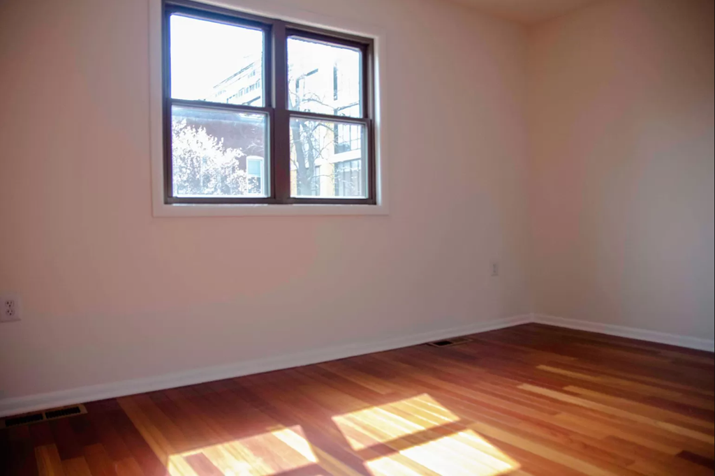 an empty room with a window and wooden floors