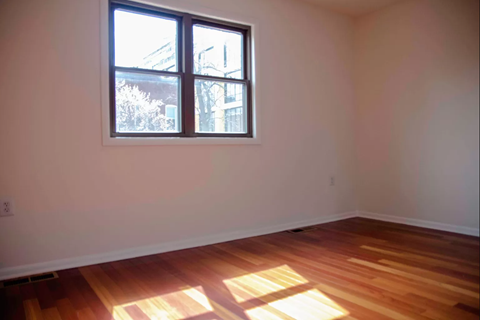 an empty room with a window and wooden floors