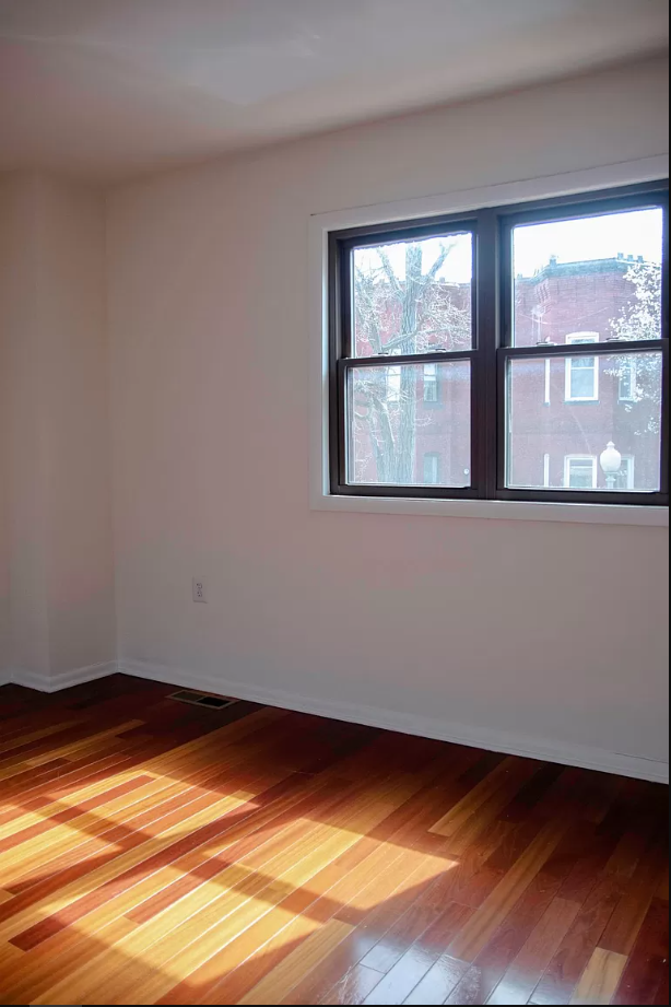 an empty room with a window and wooden floors