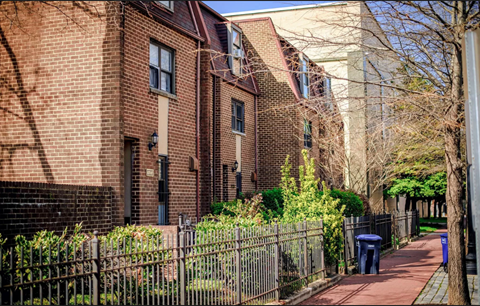 a sidewalk in front of a brick building with a metal fence