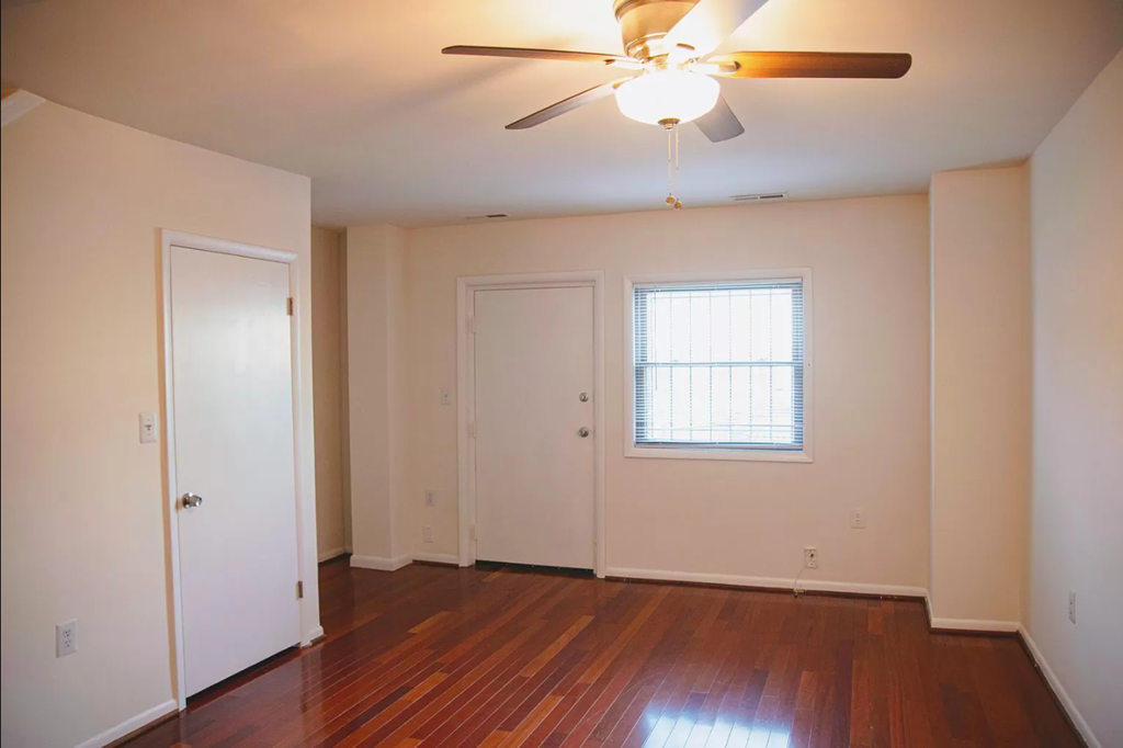 the living room of an empty house with a ceiling fan