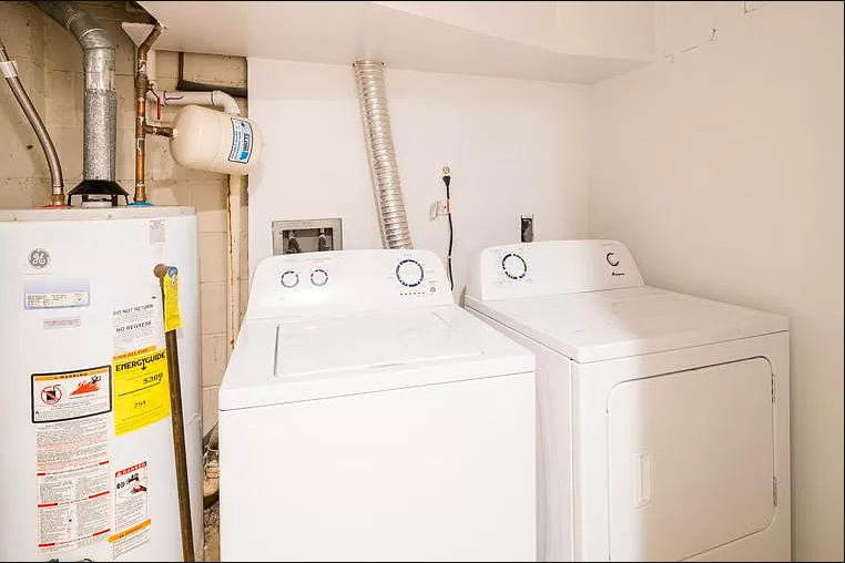two washing machines in a small room with a refrigerator