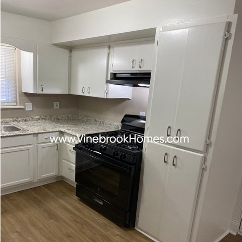 A kitchen with white cabinets and a black oven.
