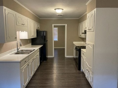 A kitchen with white cabinets and a black refrigerator.