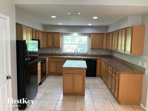 A kitchen with wooden cabinets and a black refrigerator.