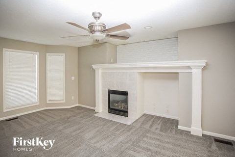 A spacious living room with a fireplace and a ceiling fan.