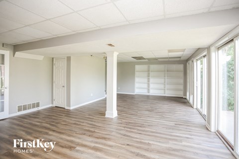 A spacious room with wooden flooring and white walls.