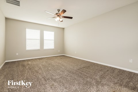 a spacious living room with carpet and a ceiling fan