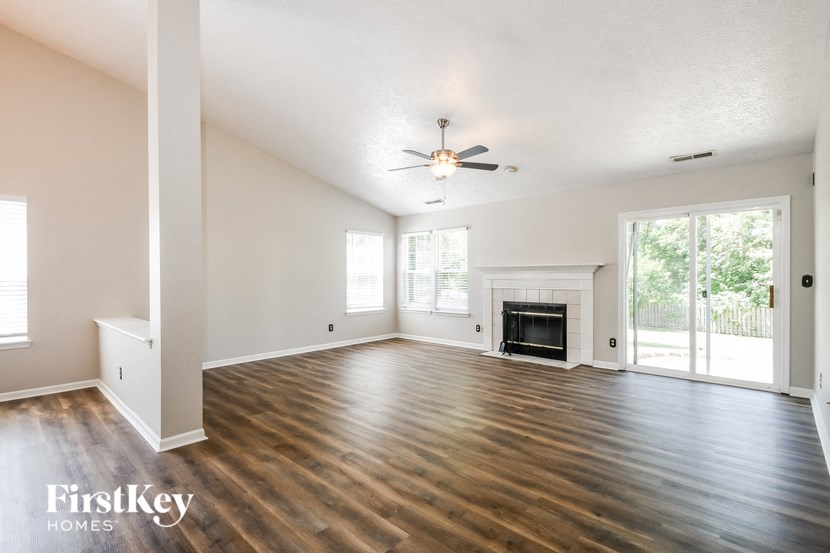 an empty living room with a ceiling fan and a fireplace