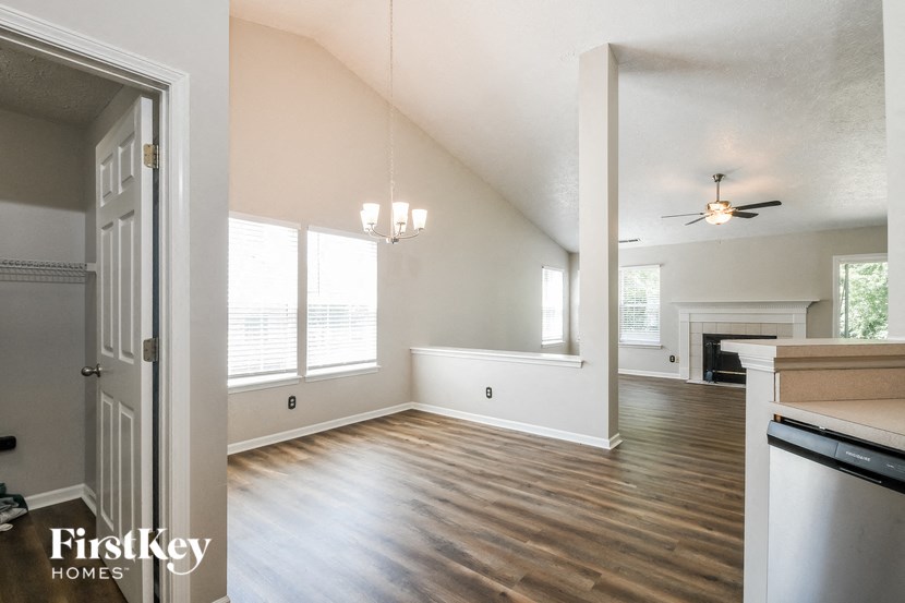 an empty living room and kitchen with a ceiling fan