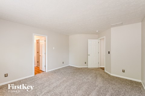 the living room and dining room of a house with white walls and carpet