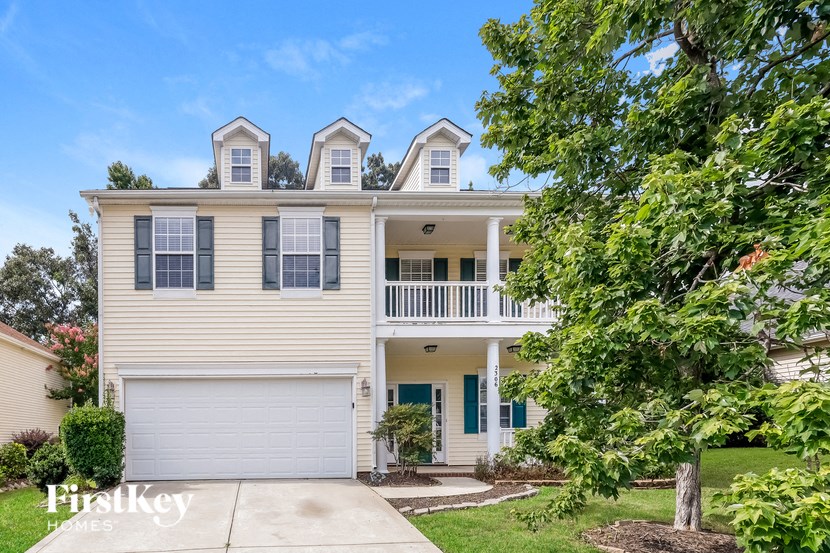 a white house with a garage and a tree