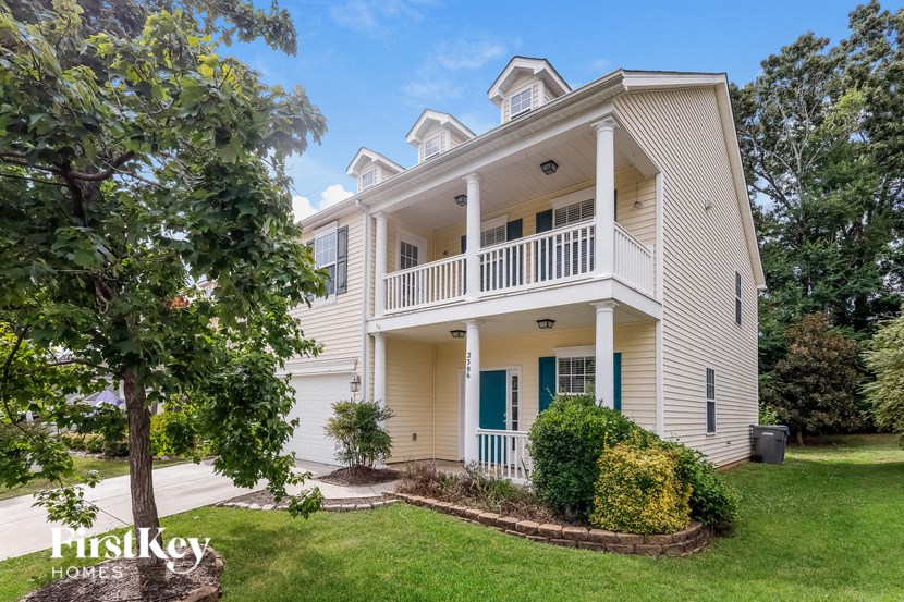 a white house with a porch and a tree