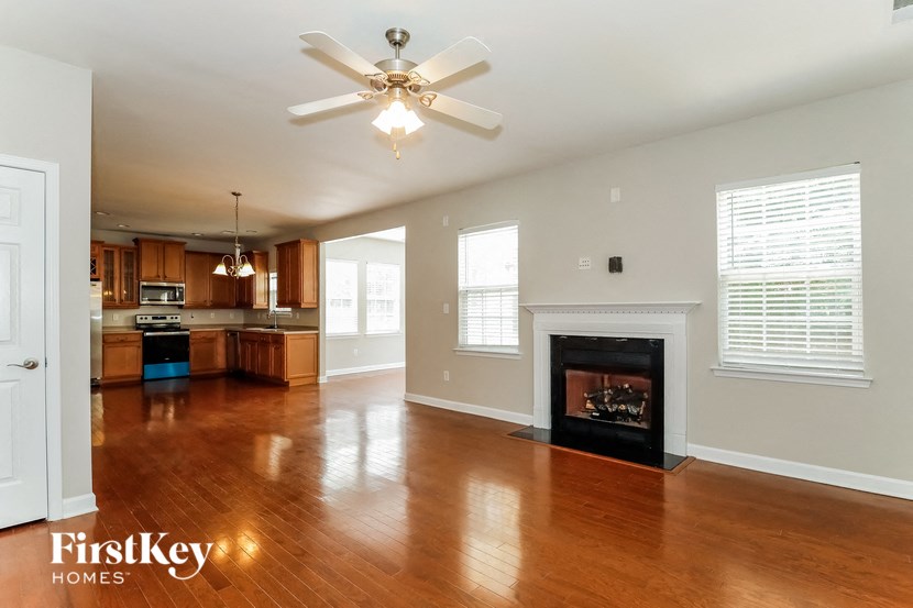 an empty living room with a fireplace and a ceiling fan