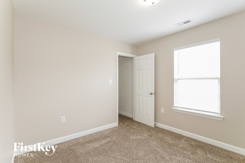 a bedroom with a door and a window and a carpeted floor