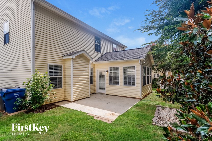 a small yellow house with a driveway and a grassy yard