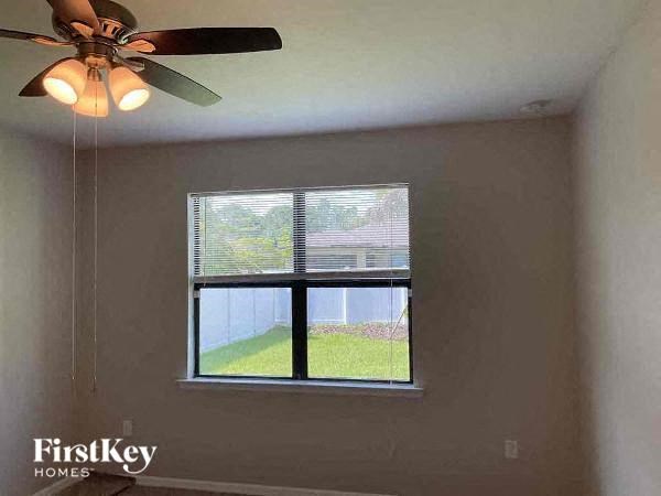 a bedroom with a window and a ceiling fan