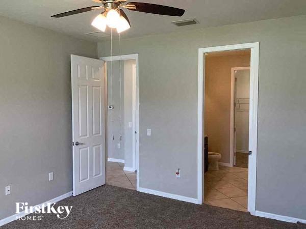 an empty room with a ceiling fan and a door to a bathroom