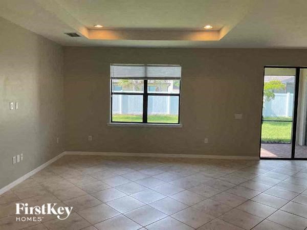 an empty living room with a window and tiled floor