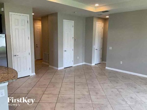an empty living room with three doors and a tiled floor