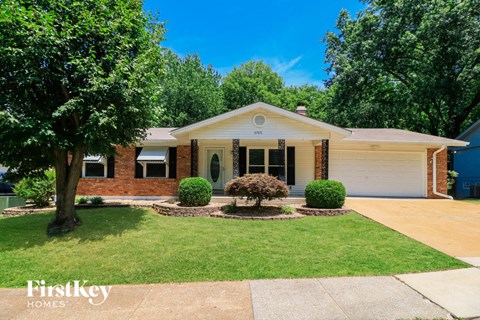 a white and brick house with a lawn and trees