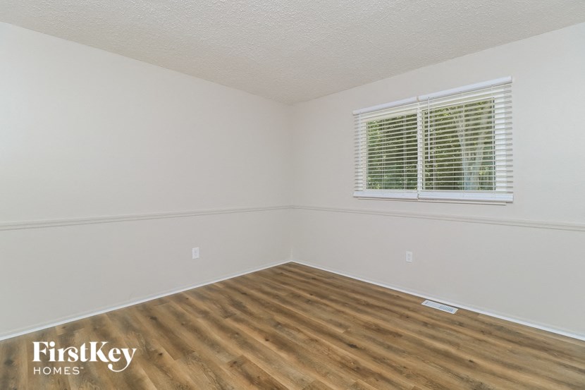 a bedroom with a wood floor and a window