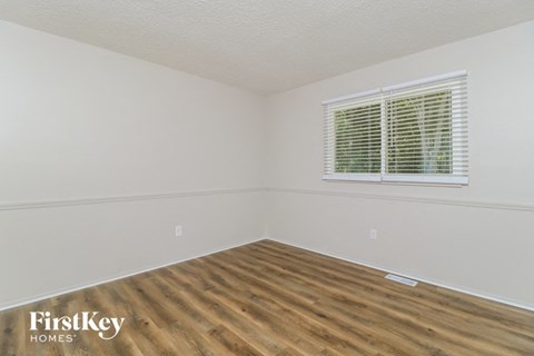 a bedroom with a wood floor and a window