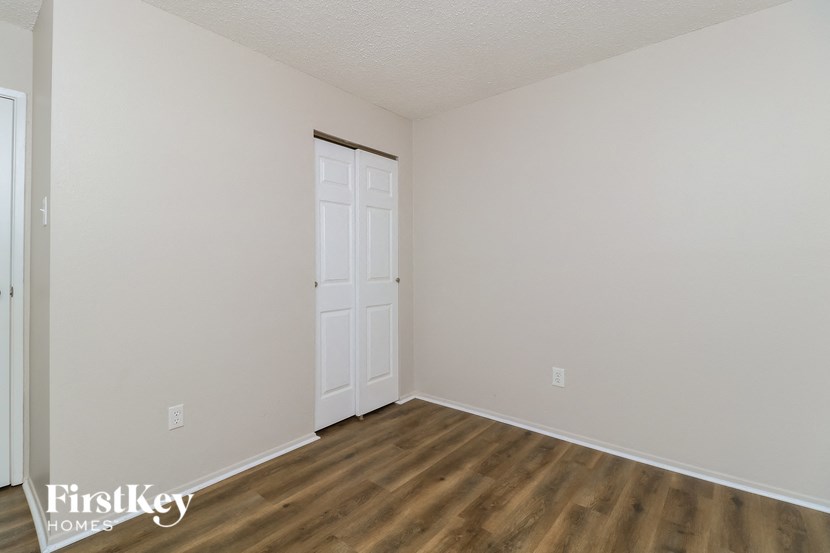 a bedroom with white walls and wood flooring and a white door