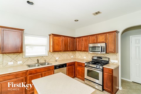 A kitchen with wooden cabinets and a stove top oven.