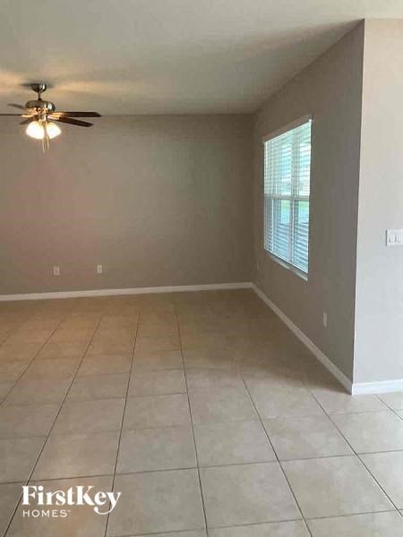 a empty living room with a ceiling fan and a tiled floor