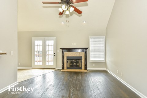 A spacious living room with a fireplace and a ceiling fan.